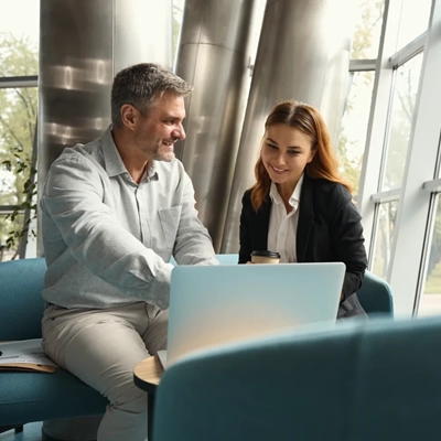 Two professionals discussing work on a laptop in a modern office, symbolizing Yiğitoğlu's vision of collaboration and growth.